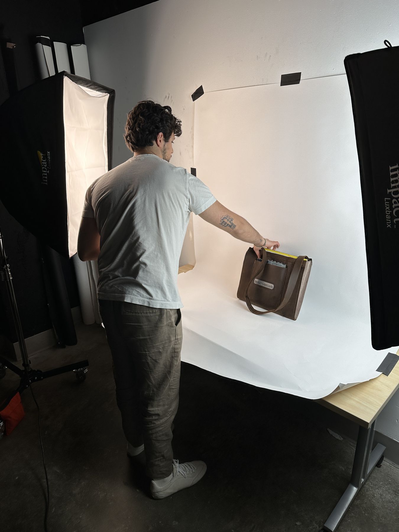 Behind the scenes — bag styled on paper sweep, softboxes in frame