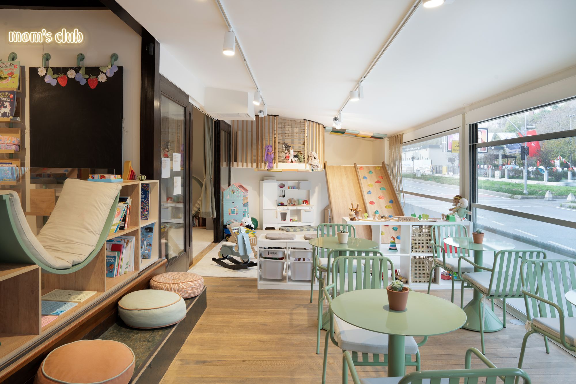 Mom's Club — interior play area with sage green chairs and climbing wall